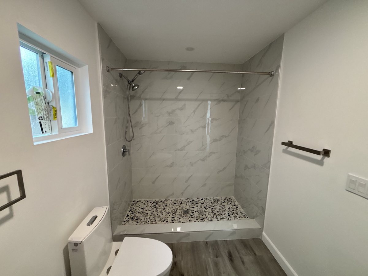 Marble walk in shower with pebble floor