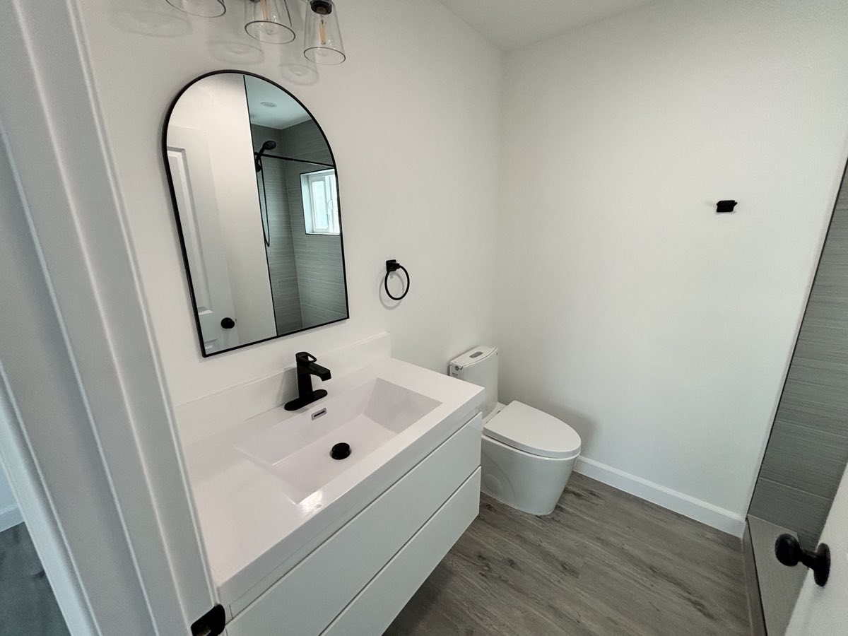 Arched mirror over floating vanity with black faucet